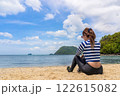 Serene Beach Scene with Woman Sitting on Shoreline and Enjoying Beautiful Ocean Views 122615082