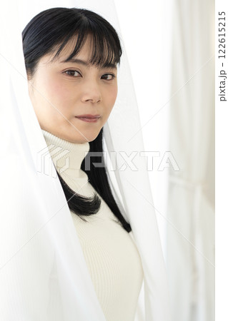 カーテンの間に立つ美しい女性のポートレート 122615215
