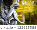 a winged angel figure in profile in an autumnal cemetery looks sadly to the ground with an outstretched hand 122615588