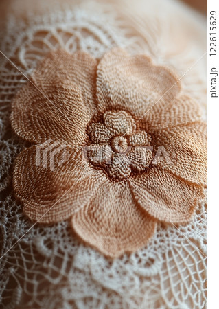 Delicate peach colored flower embroidery on beige lace, celebrating International Tatting Day. Intricate stitching and texture create a beautiful handmade detail 122615629