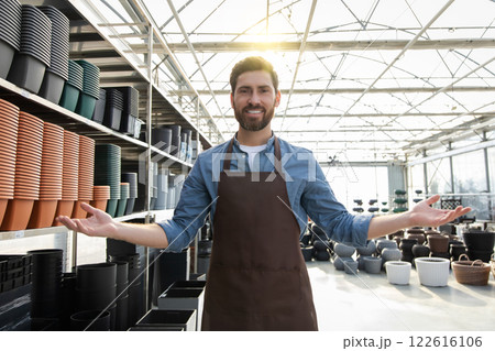 Bearded man in retail store surrounded with plastic pots for plants on shelves in shop 122616106