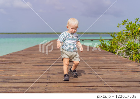 Little baby toddler exploring wooden pier over the turquoise waters of Bacalar Lake, Mexico. Peaceful tropical travel destination concept 122617338