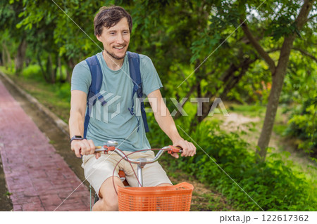 Man tourist cycling through the charming village of Bacalar, Mexico. Quintana Roo travel, scenic bike paths, and eco-friendly exploration concept Man tourist cycling through the charming village of Bacalar, Mexico. Quintana Roo travel, scenic bike paths, and eco-friendly exploration concept 122617362