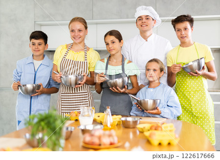 Smiling children posing with professional chef during cooking class Smiling children posing with professional chef during cooking class 122617666
