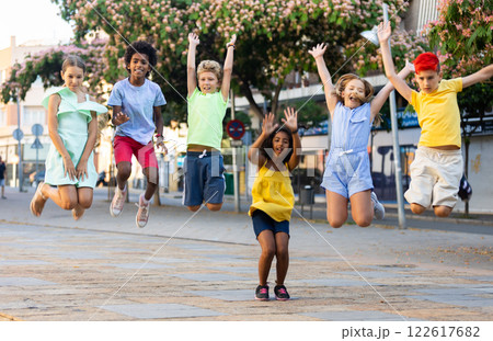 Cheerful tween girls and boys jumping together on summer city street Cheerful tween girls and boys jumping together on summer city street 122617682