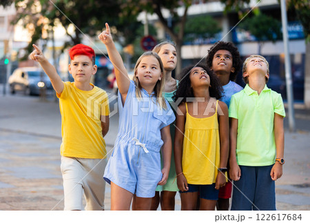 Inquisitive carefree tweens looking up at sky and pointing at something Inquisitive carefree tweens looking up at sky and pointing at something 122617684