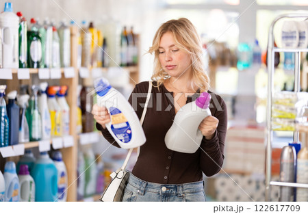 Girl housewife in household store examines goods, chooses liquid detergent 122617709