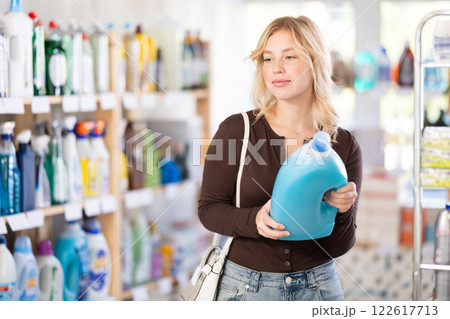 Young girl looking for household detergents on shelves in store 122617713