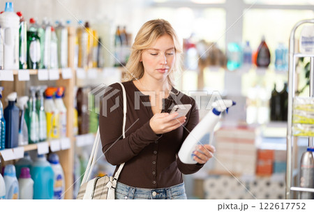 Before making purchase, girl buyer scan QR code on packaging of glass cleaner spray 122617752
