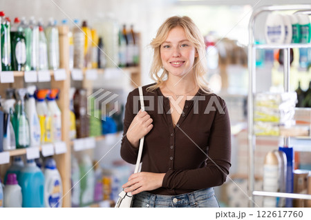 Young woman looking for something on shelf of showcase, reviews assortment in household shop Young woman looking for something on shelf of showcase, reviews assortment in household shop 122617760