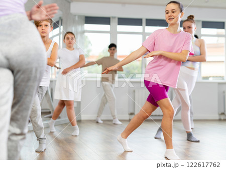 Female girl student repeats movements of unrecognizable teacher during group modern dance class. Female girl student repeats movements of unrecognizable teacher during group modern dance class. 122617762