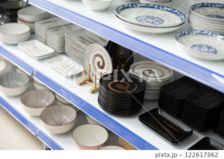 In cookware department, plates of various shapes and sizes, with different patterns, are on shelves 122617862