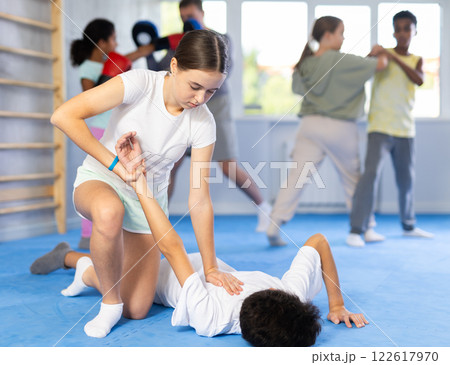 Girl practicing painful armlock in sparring with boy at self defence training Girl practicing painful armlock in sparring with boy at self defence training 122617970