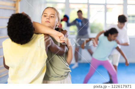 Preteen children pairs learning strength self-defense in gym Preteen children pairs learning strength self-defense in gym 122617971
