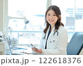 笑顔の女性医師が診察室でカルテを確認する様子 122618376