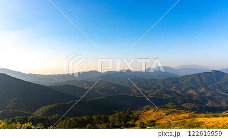 Beautiful sunrise on the mountain with fog in winter. The sun shines down on a serene mountain landscape covered with tropical trees in the early morning. Beautiful sunrise on the mountain with fog in winter. The sun shines down on a serene mountain landscape covered with tropical trees in the early morning. 122619959