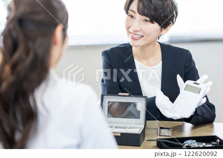 計算機で査定金額を説明する買取専門業者 122620092