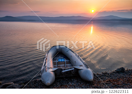 Rubber boat on the shore of the picturesque coast against the backdrop of sunrise 122622311