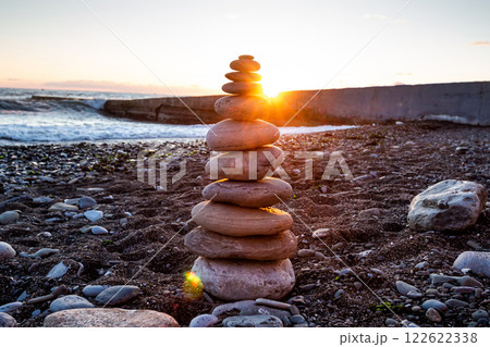 Pyramid of pebbles on the seashore at sunset 122622338