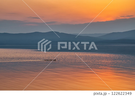 A beautiful lake against the backdrop of a picturesque sunset. Duck family on the water A beautiful lake against the backdrop of a picturesque sunset. Duck family on the water 122622349