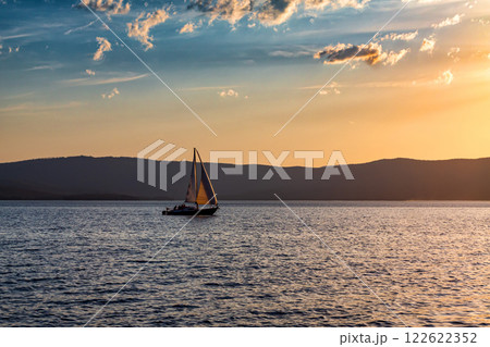 Yacht on a scenic lake in beautiful evening light Yacht on a scenic lake in beautiful evening light 122622352