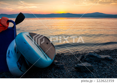 Two sup boards on the shore of a scenic lake against the backdrop of sunset Two sup boards on the shore of a scenic lake against the backdrop of sunset 122622359