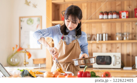 キッチンで料理をする女性（パスタを盛り付ける） 122622405