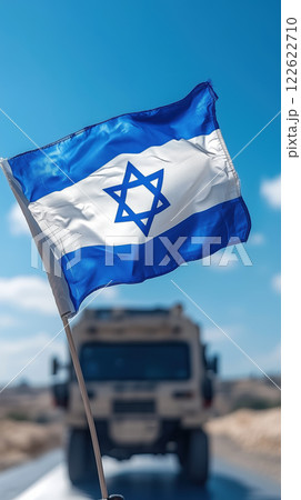 Israeli flag waving in wind with military vehicle in background 122622710