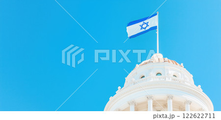 Israel flag waving proudly against clear blue sky above dome 122622711