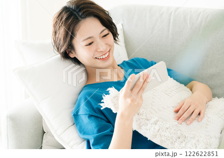 寝転んでスマホを見る若い女性 122622851