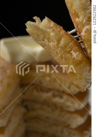 蜂蜜をかけたホットケーキをフォークで持ち上げる 122622982