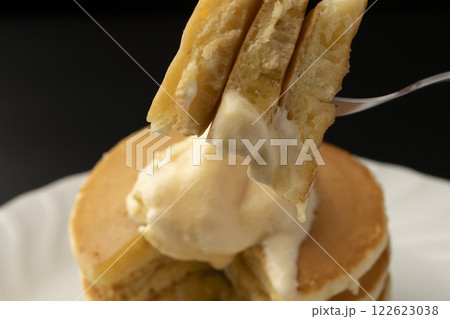 アイスクリームを乗せたホットケーキをフォークで持ち上げる 122623038