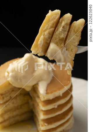 アイスクリームを乗せたホットケーキをフォークで持ち上げる アイスクリームを乗せたホットケーキをフォークで持ち上げる 122623040