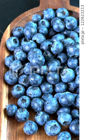 Blueberries grouped on brown wood emphasize rustic appeal and connection to eco lifestyle. Each berry represents symbol of summer harvest, showcasing eco-friendly values, highlighting natural symbol. 122623213