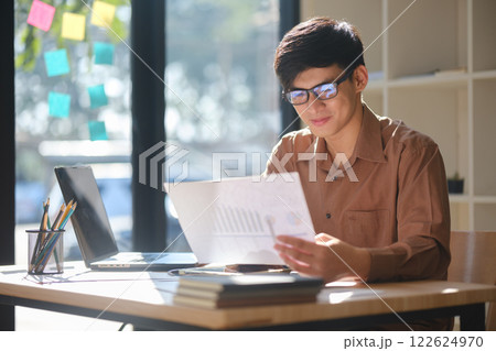Young businessman analyzing financial data and market trends for investment decisions Young businessman analyzing financial data and market trends for investment decisions 122624970