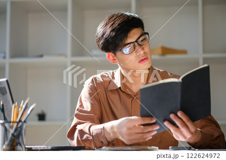 Young man studying online and researching financial concepts for education and career development Young man studying online and researching financial concepts for education and career development 122624972