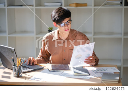 Young businessman analyzing financial data and market trends for investment decisions Young businessman analyzing financial data and market trends for investment decisions 122624973