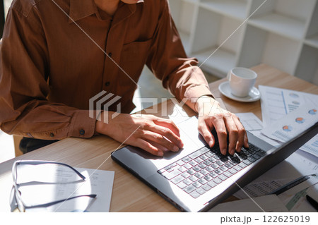 Close-up of hands typing on a laptop keyboard, working on business analysis and online learning. 122625019