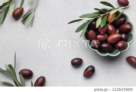 Kalamata olives with olive branch in green bowl on marble background Kalamata olives with olive branch in green bowl on marble background 122625609