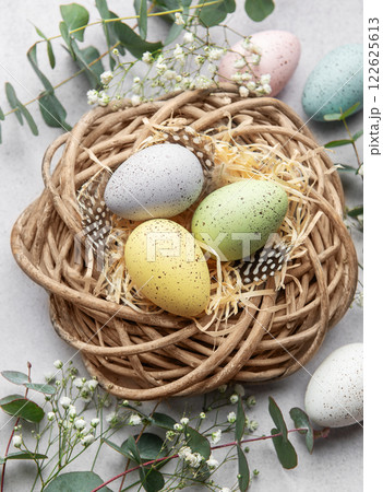 Easter eggs lying in nest surrounded by flowers and eucalyptus leaves 122625613