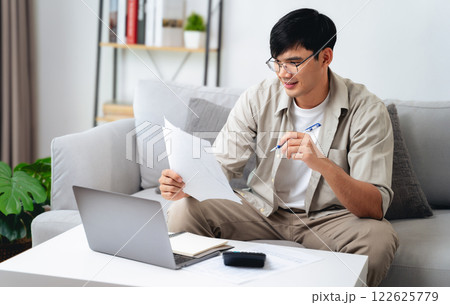 Man is calculating annual tax with calculator and filling form of Individual Income Tax Return. Man is calculating annual tax with calculator and filling form of Individual Income Tax Return. 122625779