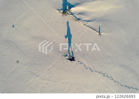 Drone photography of hiker with trekking poles climbing hill with snow Drone photography of hiker with trekking poles climbing hill with snow 122626893