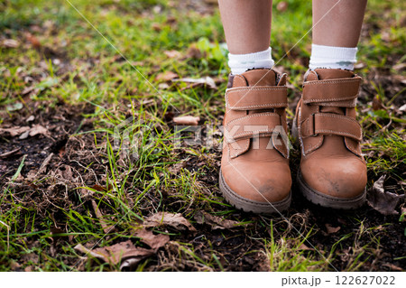 Childs brown boots on grass with autumn leaves Childs brown boots on grass with autumn leaves 122627022