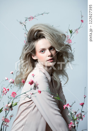 Beautiful woman with big wavy hair and flowers studio portrait 122627395