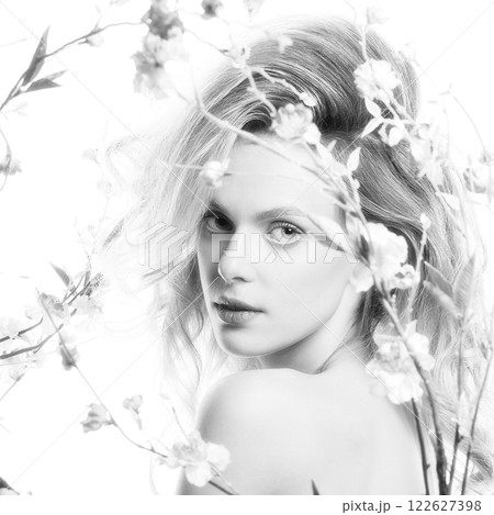 Beautiful woman with big wavy hair and flowers black and white studio portrait 122627398