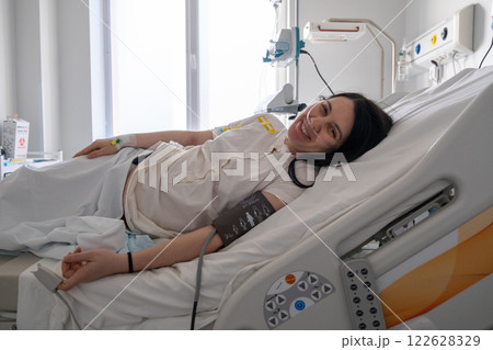 Smiling Woman in Hospital Bed with Blood Pressure Cuff 122628329