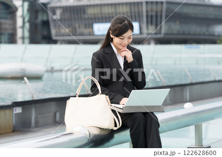 屋外でノートパソコンを見て微笑むビジネスウーマン　名古屋　栄　OASIS21　水の宇宙船にて 122628600