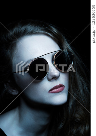Beautiful woman with sunglasses close-up studio portrait in blue tint color effect Beautiful woman with sunglasses close-up studio portrait in blue tint color effect 122630559
