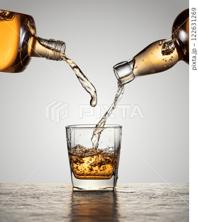 Whiskey is poured from a bottles into a glass. Whiskey is poured from a bottles into a glass. 122631269