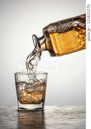 Whiskey is poured into a glass with ice. Whiskey is poured into a glass with ice. 122631270